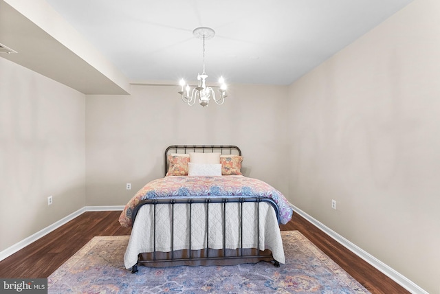 bedroom featuring a notable chandelier, baseboards, and wood finished floors