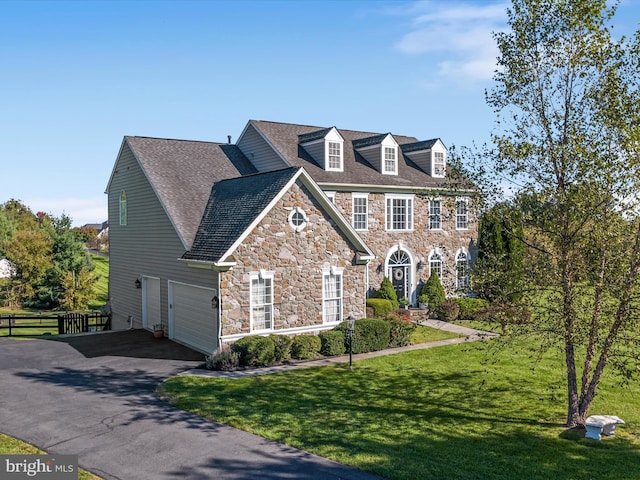 colonial-style house with aphalt driveway, a front yard, a garage, and fence