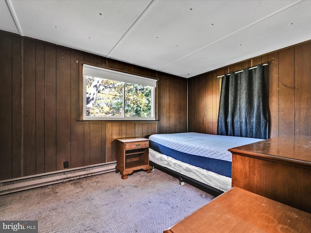 carpeted bedroom featuring baseboard heating, a textured ceiling, and wooden walls