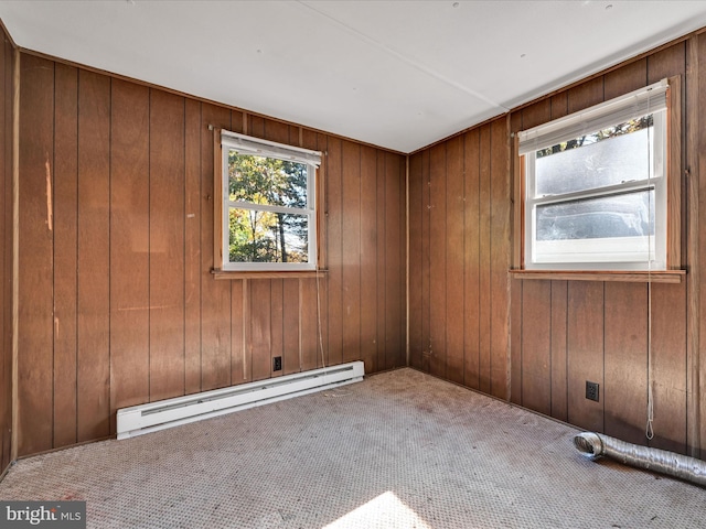 carpeted spare room with a baseboard radiator and wood walls