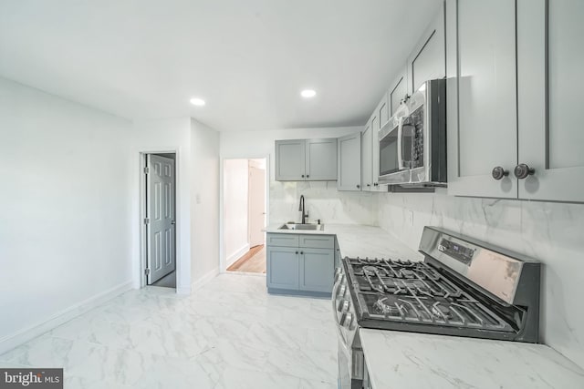 kitchen with appliances with stainless steel finishes, light stone countertops, sink, and backsplash