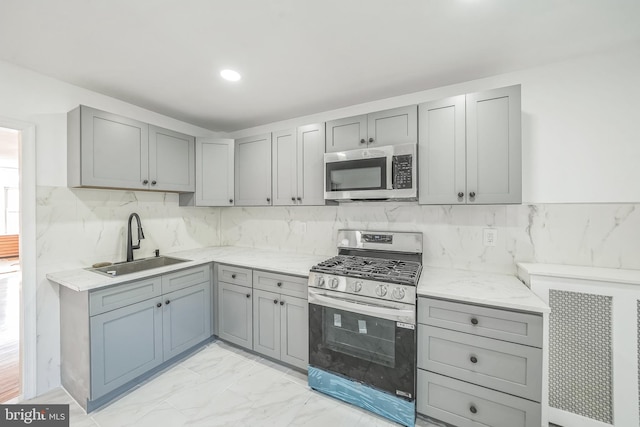 kitchen with gas range, decorative backsplash, sink, and gray cabinets