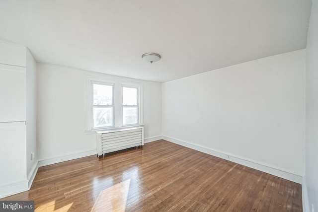 spare room featuring radiator and hardwood / wood-style floors