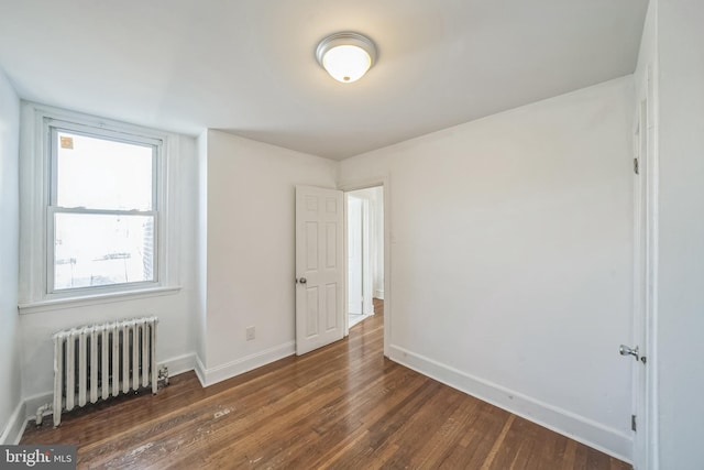 empty room with radiator heating unit and dark hardwood / wood-style floors