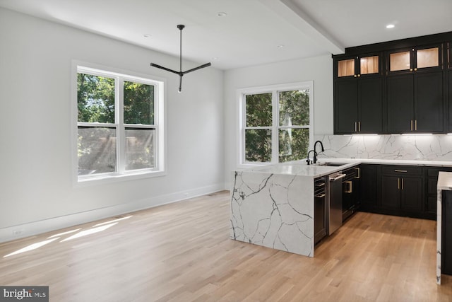 kitchen featuring light stone countertops, light wood-type flooring, a wealth of natural light, and sink