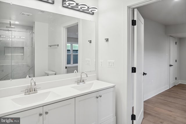 bathroom with hardwood / wood-style flooring, vanity, toilet, and walk in shower