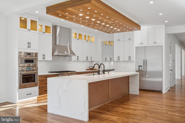 4609 Willow Run Dr, Annandale, VA 22003 - kitchen with stainless steel appliances, wall chimney range hood, recessed lighting, a sink, and light wood finished floors