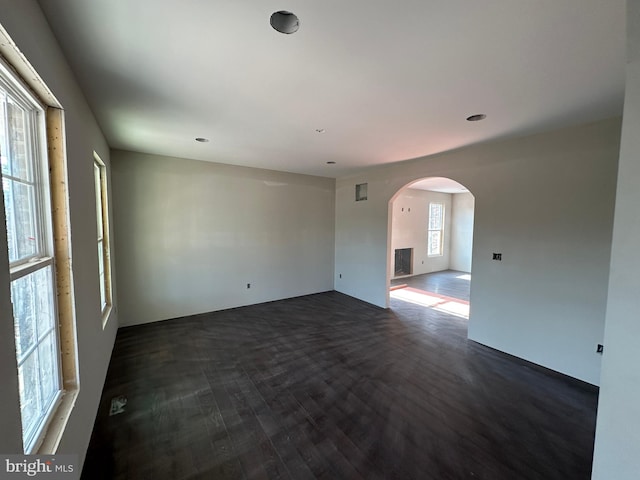 empty room with dark colored carpet and plenty of natural light