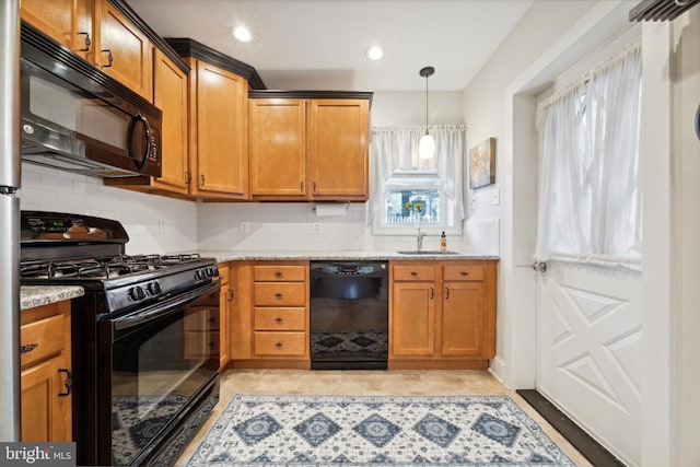 kitchen featuring black appliances, sink, tasteful backsplash, light stone countertops, and pendant lighting