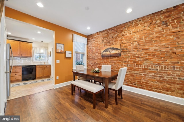 dining area featuring dark hardwood / wood-style flooring, brick wall, and sink