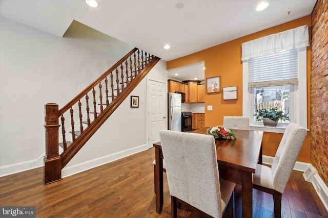 dining area featuring brick wall and dark hardwood / wood-style flooring