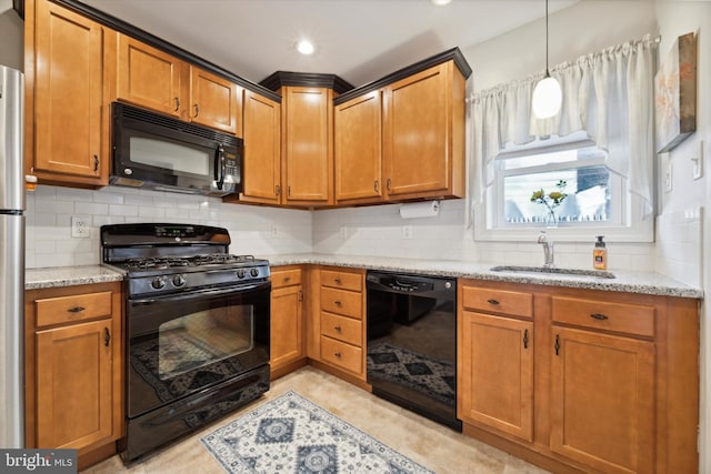 kitchen with light stone counters, decorative backsplash, black appliances, sink, and pendant lighting