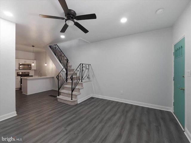 unfurnished living room featuring ceiling fan, sink, and dark hardwood / wood-style flooring