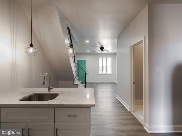 kitchen featuring light stone counters, ceiling fan, dark hardwood / wood-style flooring, sink, and decorative light fixtures