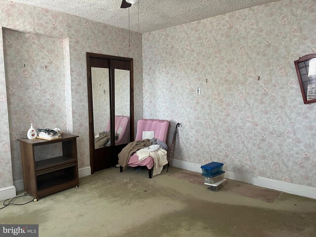 unfurnished room featuring a textured ceiling, carpet floors, and ceiling fan