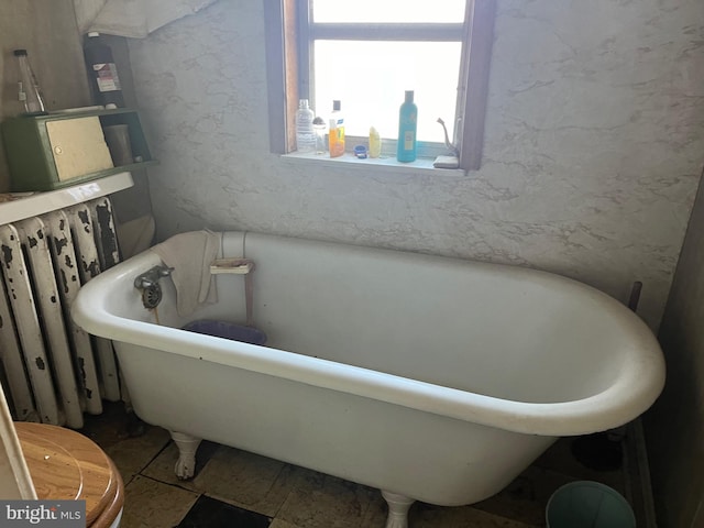 bathroom with a bathing tub, toilet, and radiator