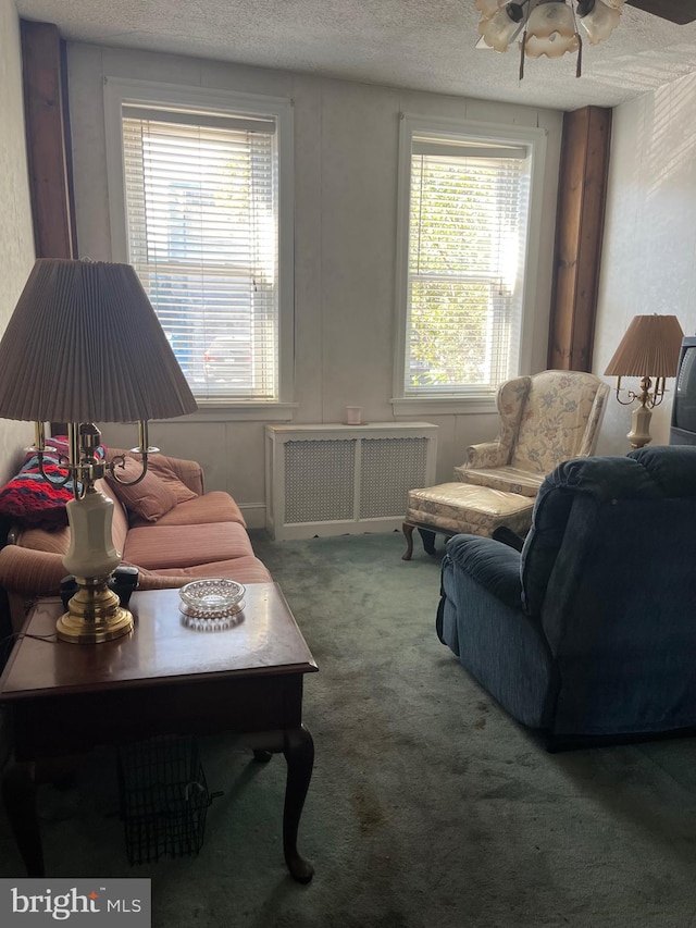 carpeted living room with a textured ceiling, ceiling fan, radiator heating unit, and plenty of natural light