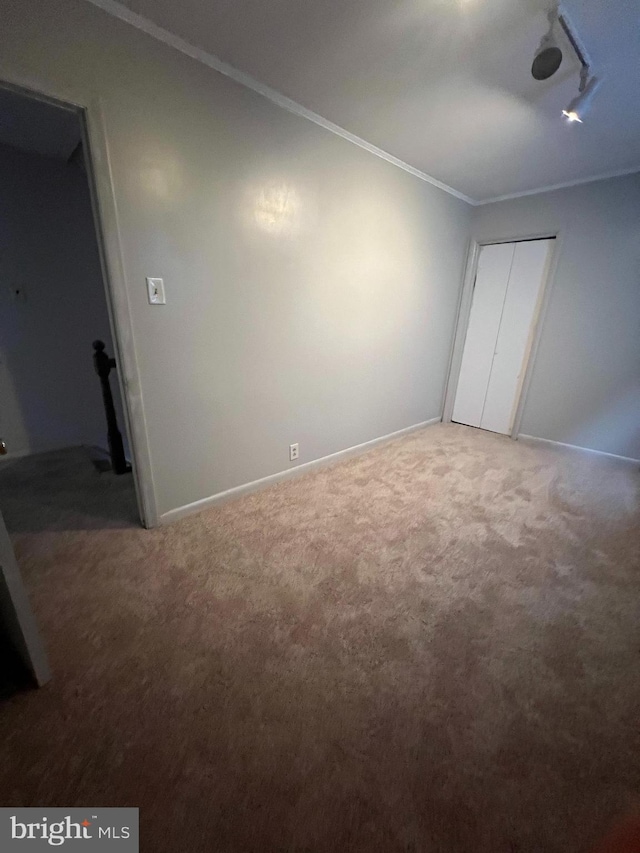 unfurnished bedroom with a closet, carpet floors, and crown molding