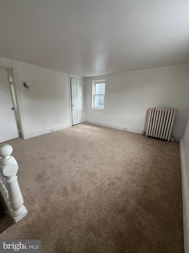 unfurnished room featuring radiator and carpet floors