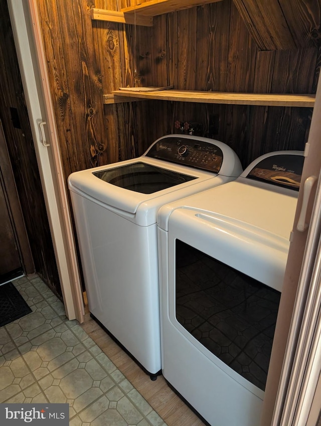 laundry area with washing machine and dryer and wooden walls