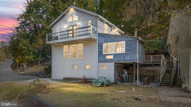 back house at dusk featuring a balcony