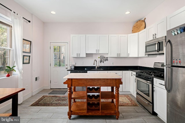 kitchen featuring white cabinets, stainless steel appliances, sink, and light wood-type flooring