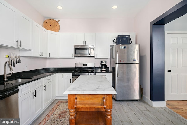 kitchen featuring white cabinetry, appliances with stainless steel finishes, sink, and light wood-type flooring