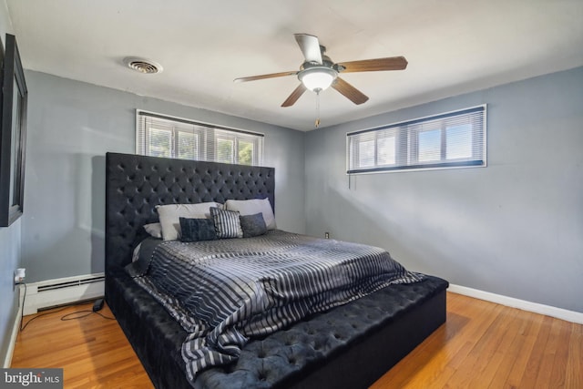 bedroom with light hardwood / wood-style floors, a baseboard radiator, and ceiling fan