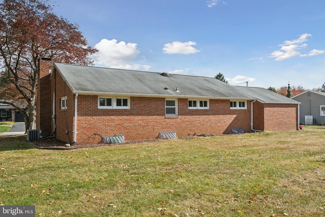 back of property featuring central AC and a lawn