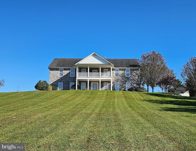 back of property with a balcony and a lawn