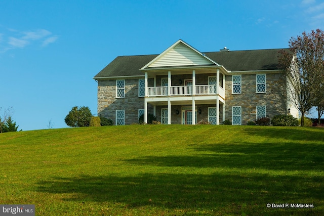 view of front of house featuring a balcony and a front lawn