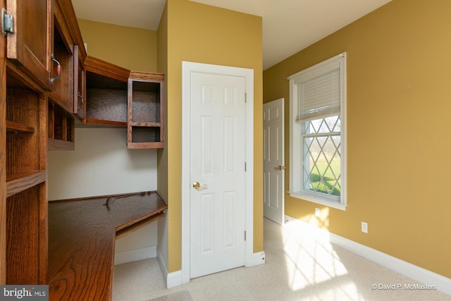 interior space with built in desk and light colored carpet