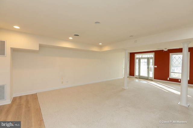 empty room with light wood-type flooring, french doors, and ornate columns