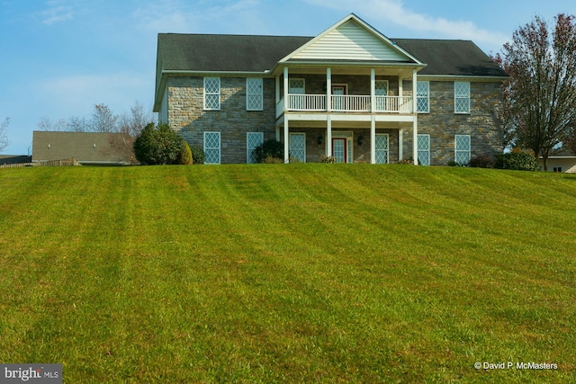 view of front facade with a front yard and a balcony