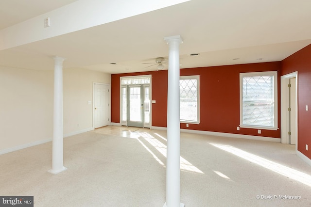 carpeted empty room featuring ornate columns and ceiling fan