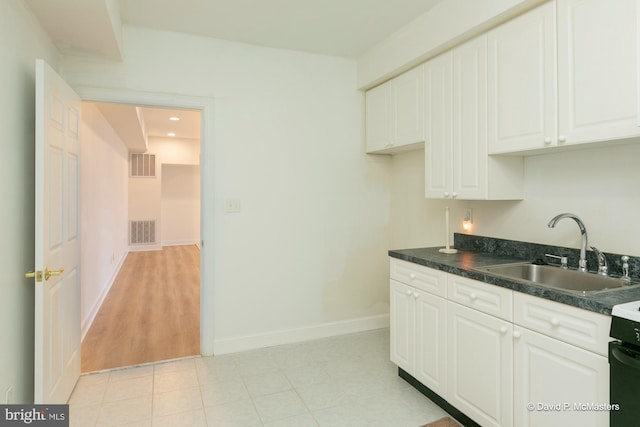 kitchen featuring white cabinetry, range, and sink