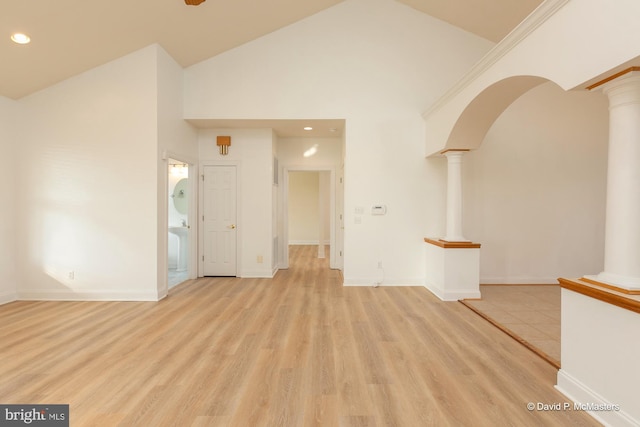 unfurnished living room with light hardwood / wood-style floors, high vaulted ceiling, and ornate columns