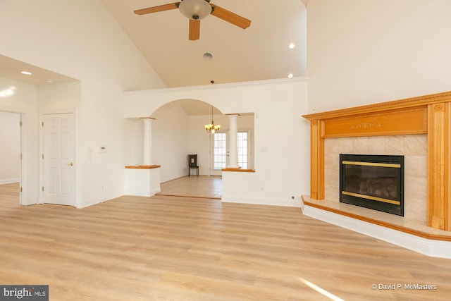 unfurnished living room with light hardwood / wood-style floors, high vaulted ceiling, a tile fireplace, and ceiling fan