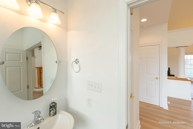 bathroom with ornate columns, wood-type flooring, and sink