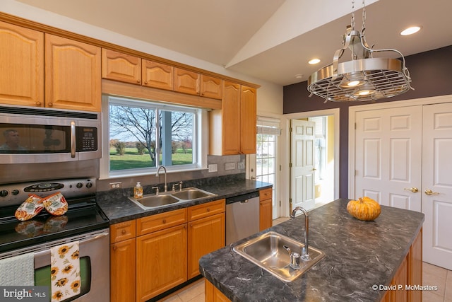 kitchen featuring vaulted ceiling, appliances with stainless steel finishes, sink, and a center island with sink