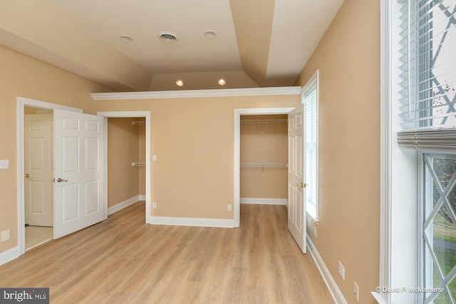 unfurnished bedroom with a walk in closet, a closet, and light wood-type flooring