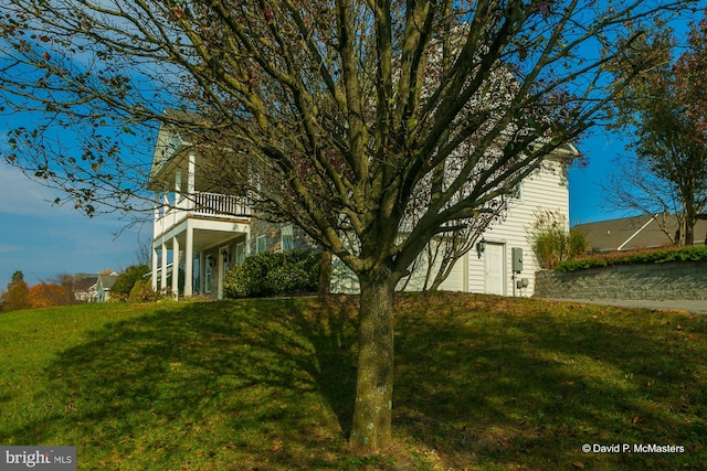 view of side of property featuring a balcony and a lawn