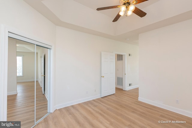 unfurnished room featuring ceiling fan, a tray ceiling, and light hardwood / wood-style floors