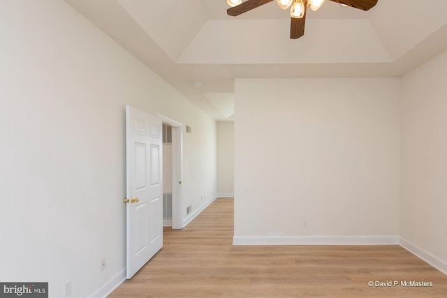 spare room with ceiling fan, a tray ceiling, and light wood-type flooring