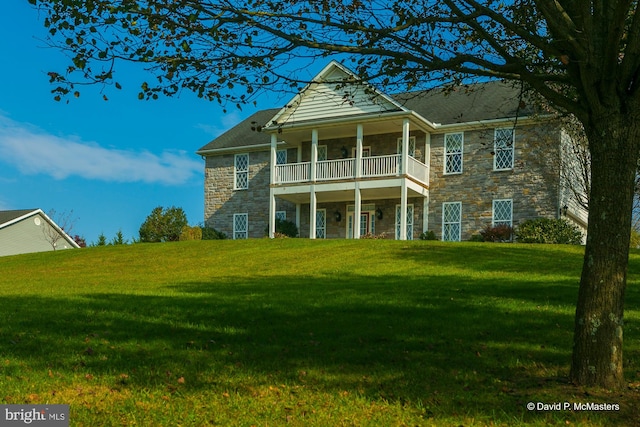 view of front facade featuring a front yard and a balcony