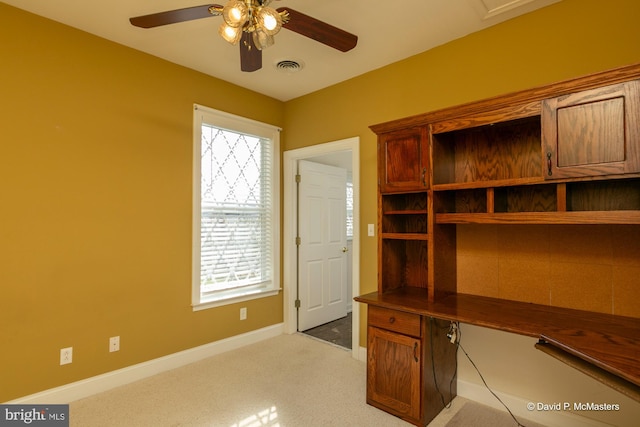 unfurnished office featuring plenty of natural light, light carpet, and ceiling fan