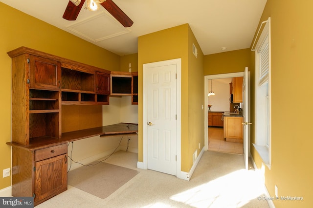 carpeted office space featuring ceiling fan and built in desk