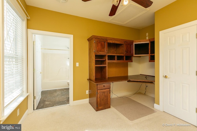 carpeted home office with ceiling fan, built in desk, and a wealth of natural light