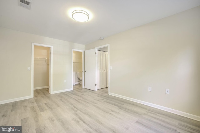 unfurnished bedroom with light hardwood / wood-style floors, a walk in closet, and a closet