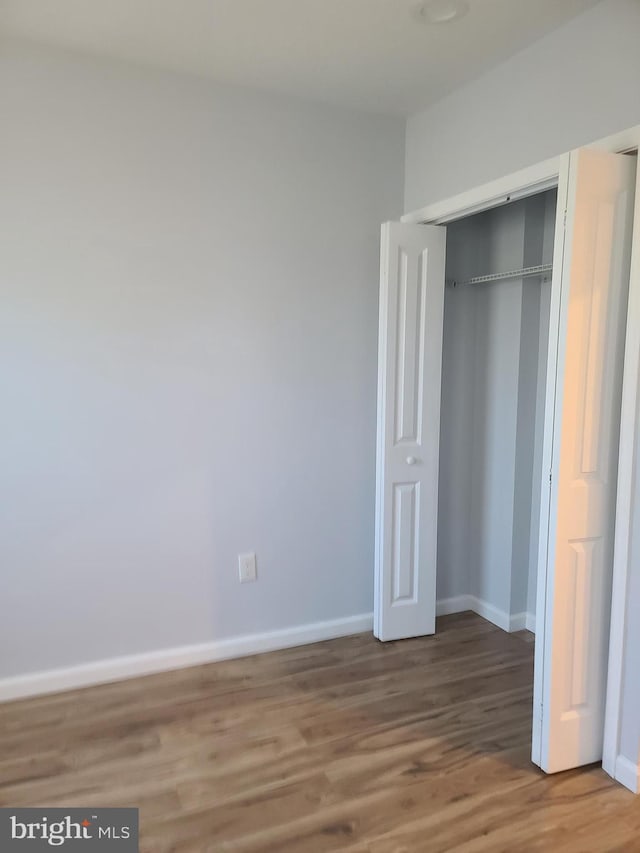 unfurnished bedroom featuring a closet, baseboards, and wood finished floors